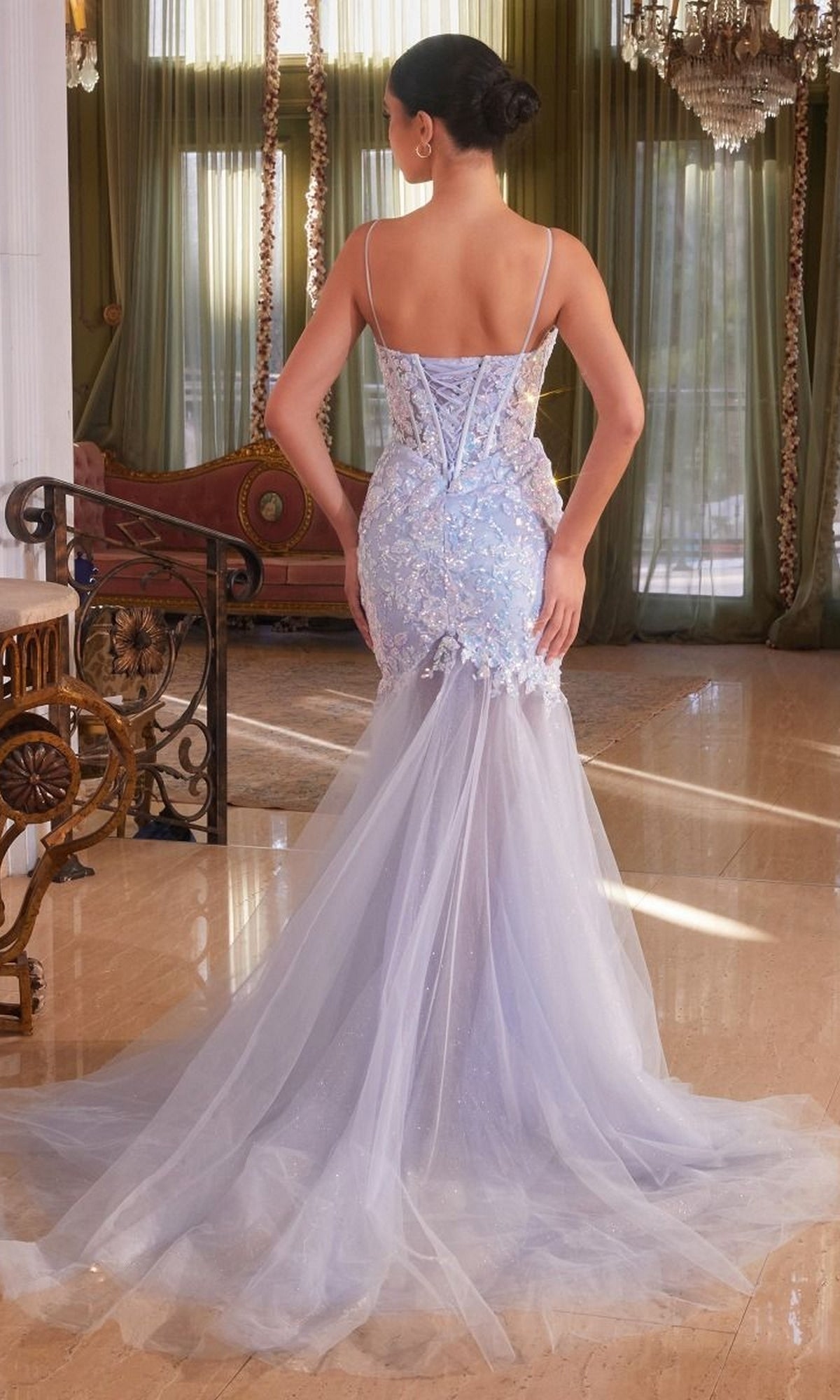 A woman in the Long Blue Sequin Mermaid Prom Dress (CB148), a sparkling, floor-length blue gown with a fitted silhouette, stands with her back to the camera in a lavish room with marble floors and green curtains.